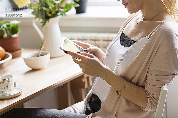 Frau benutzt Tablet-Computer  während sie am Tisch sitzt