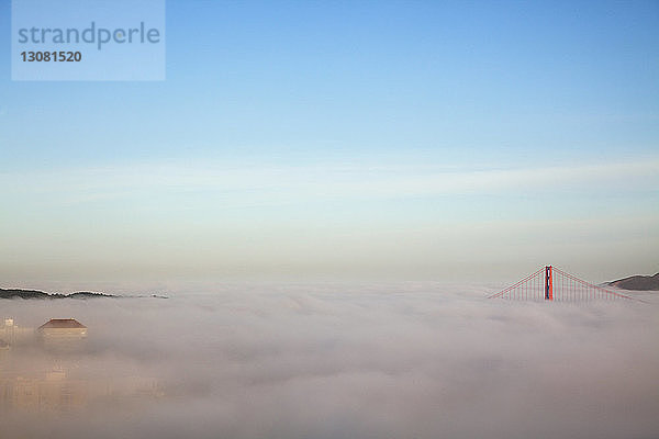 Majestätische Ansicht der Wolken  die die Golden Gate Bridge vor blauem Himmel bedecken