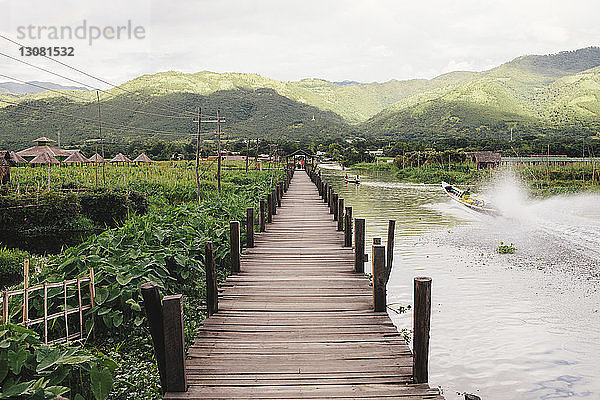 Fussgängerbrücke über den Inle-See durch Feld gegen Berge