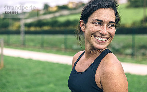 Glückliche Sportlerin schaut weg  während sie im Park trainiert