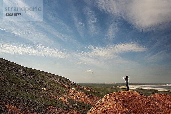 Seitenansicht einer Frau  die fotografiert  während sie auf einem Berg gegen den Himmel steht