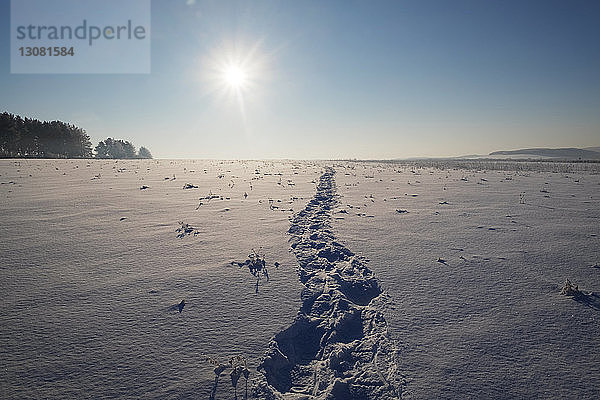Szenische Ansicht eines schneebedeckten Feldes gegen den Himmel an einem sonnigen Tag