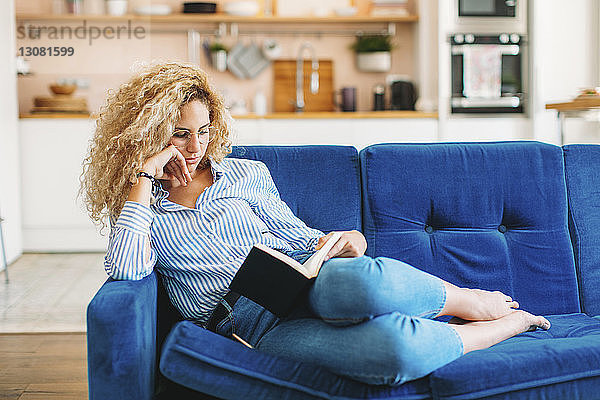 Frau liest Tagebuch in voller Länge  während sie zu Hause auf dem Sofa liegt