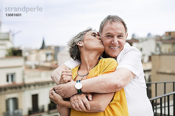 Romantische reife Frau küsst älteren Mann auf Terrasse