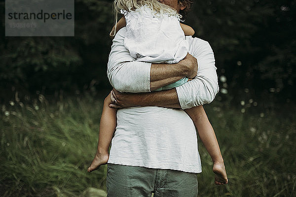 Mitten im Grasfeld: Vater umarmt Tochter