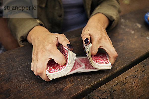 Ausgeschnittenes Bild einer Frau  die eine Spielkarte mischt