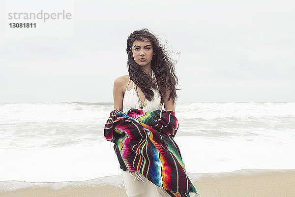 Porträt einer Frau  die eine Decke hält  während sie am Strand steht