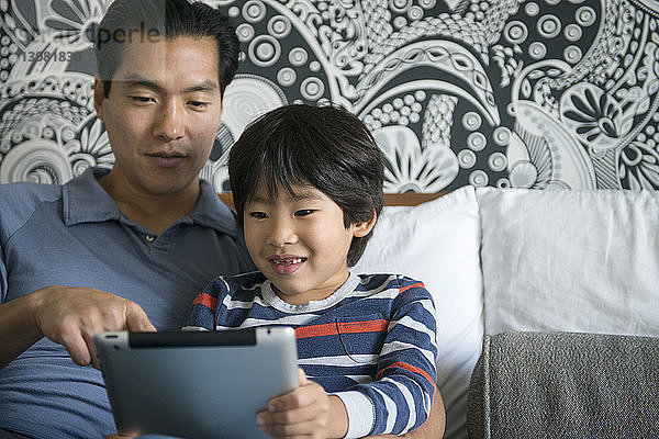 Nahaufnahme von Vater und Sohn mit digitalem Tablett am Bett