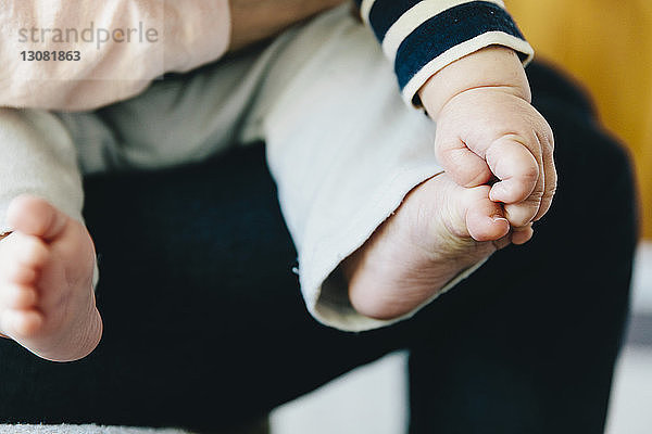 Mittelteil der Mutter  die den Sohn hält  während sie zu Hause sitzt