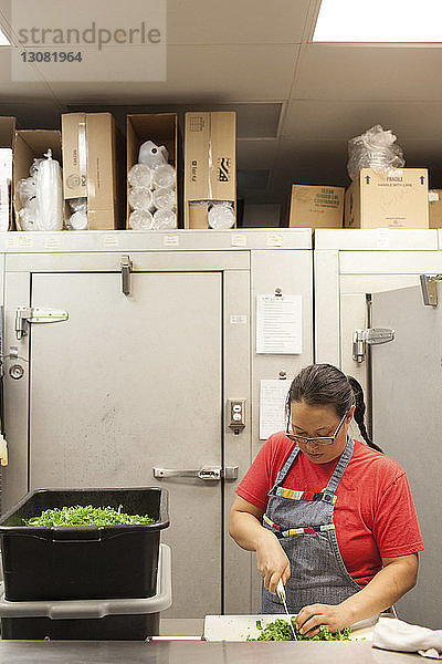 Küchenchefin hackt Gemüse auf dem Küchentisch im Restaurant