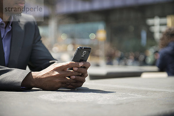 Ausgeschnittenes Bild eines Geschäftsmannes mit einem Smartphone auf dem Tisch