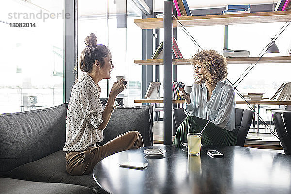 Fröhliche Geschäftsfrauen diskutieren bei einem Kaffee im Café
