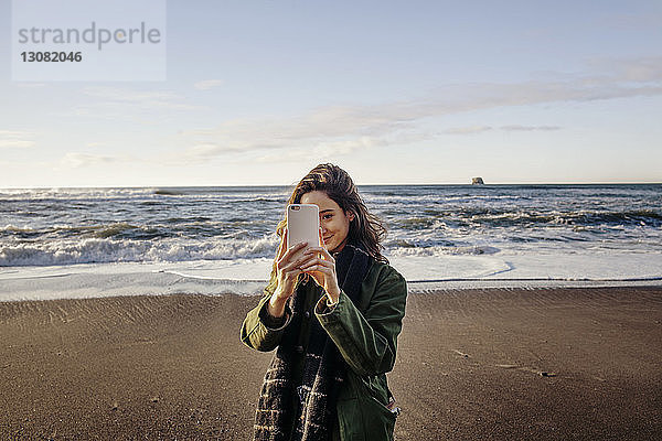 Schöne Frau fotografiert durch Smartphone-Strand