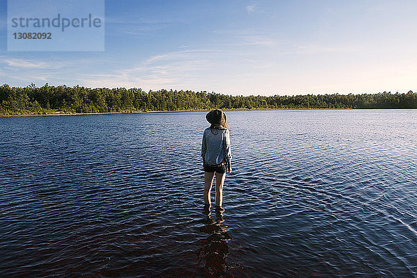 Rückansicht einer Frau  die im See steht und auf die Aussicht schaut
