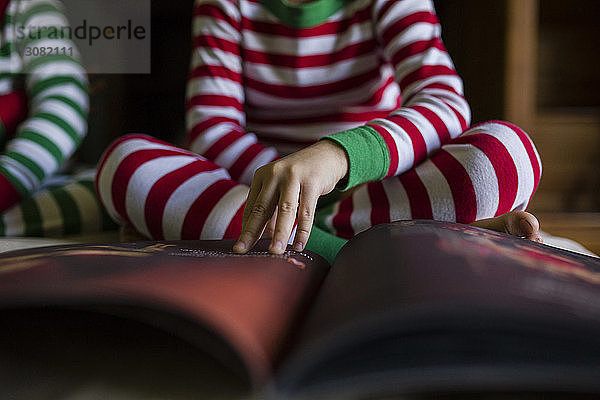 Mittelteil der Geschwister  die zu Hause sitzend ein Buch lesen