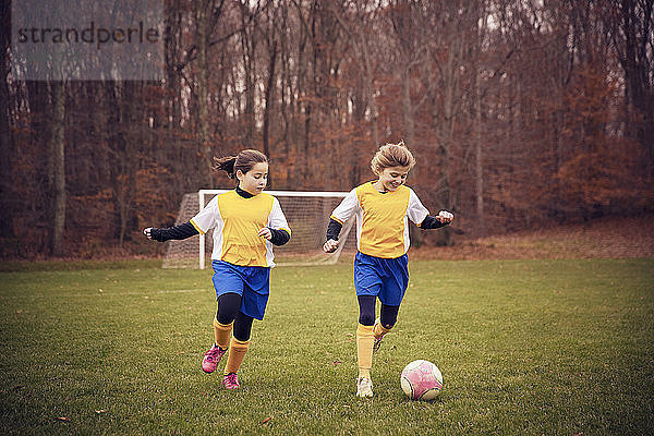 Glückliche Fußballspieler spielen auf dem Feld gegen Bäume