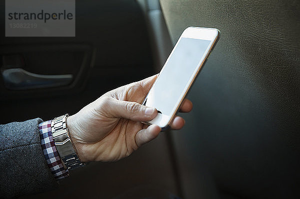 Ausgeschnittenes Bild eines Mannes  der ein Mobiltelefon während einer Autofahrt benutzt