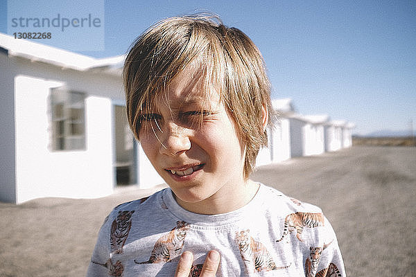 Nahaufnahme-Porträt eines Jungen gegen Häuser an einem sonnigen Tag
