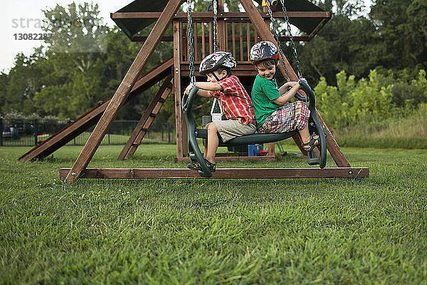 Verspielte Brüder schaukeln auf dem Spielplatz