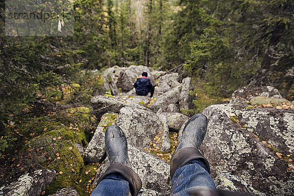 Auf Felsen sitzender Wanderer im Wald