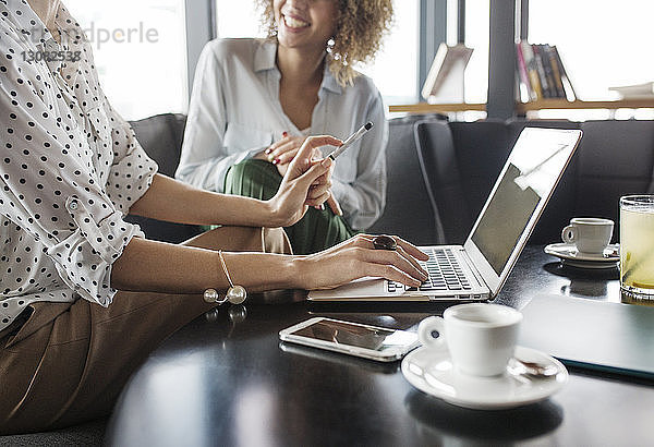 Mitschnitt einer Geschäftsfrau  die am Laptop arbeitet  während sie neben einem Kollegen im Café sitzt