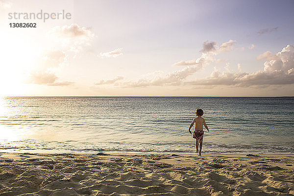 Rückansicht eines Jungen  der an einem sonnigen Tag in Richtung Strand gegen den Himmel läuft