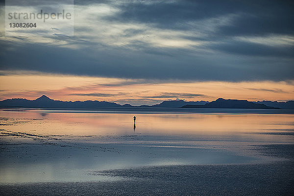 Silhouetten-Person steht auf Bonneville Salt Flats vor bewölktem Himmel