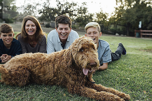 Glückliche Familie mit irischem Wolfshund auf Grasfeld im Park liegend