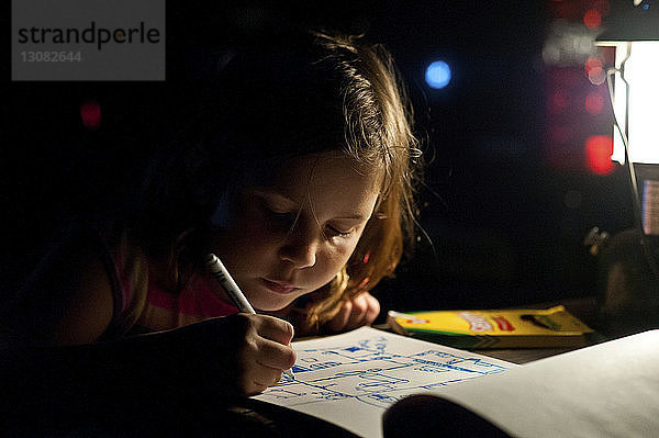 Nahaufnahme einer Mädchenzeichnung auf einem Buch in der Dunkelkammer zu Hause