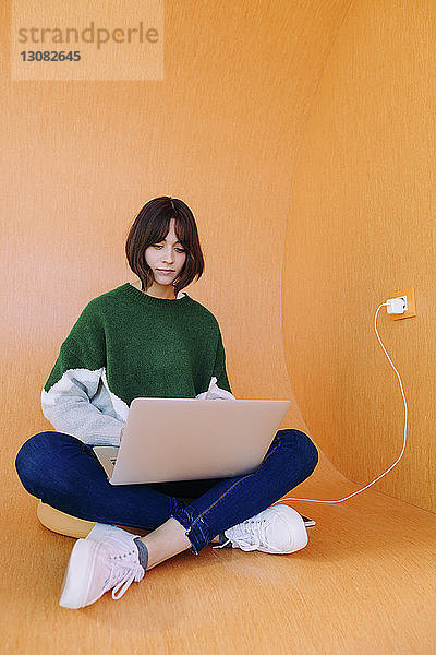 Frau benutzt Laptop-Computer  während sie in der Bibliothek sitzt