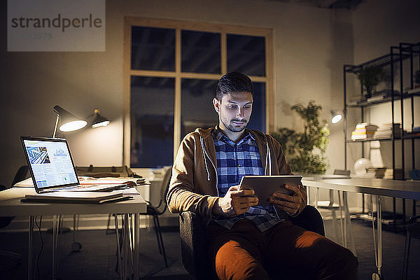 Mann lernt nachts mit Tablet-Computer in der Bibliothek