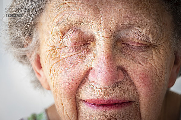 Nahaufnahme einer traurigen älteren Frau mit geschlossenen Augen