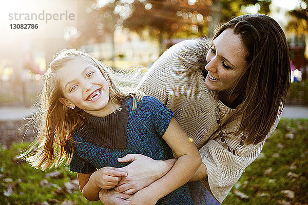 Fröhliche Mutter spielt im Herbst mit Tochter im Park