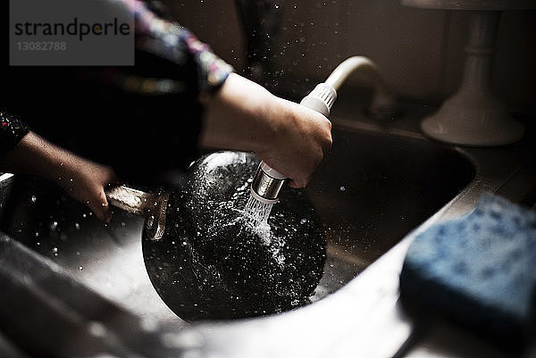 Beschnittenes Bild eines Mädchens  das einen Kochtopf an der Küchenspüle wäscht