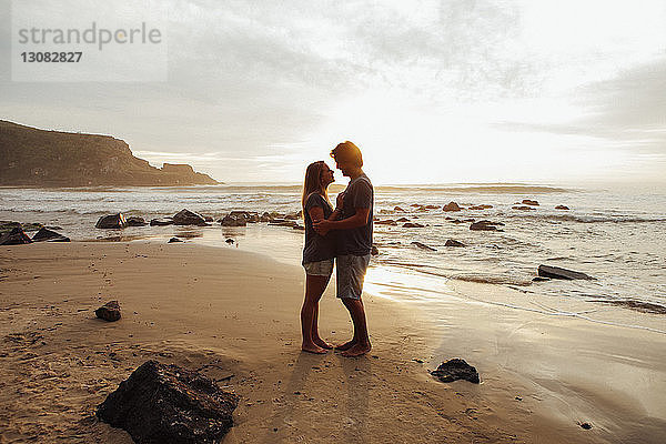 Seitenansicht eines romantischen Paares  das sich am Strand gegenübersteht