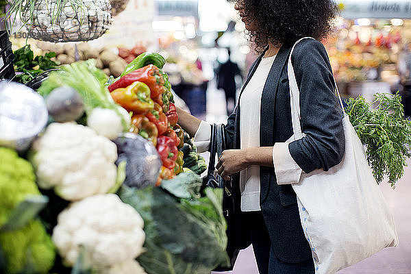 Seitenansicht einer Frau  die Gemüse auf dem Markt kauft