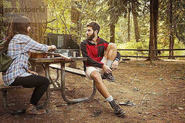 Freunde unterhalten sich am Picknicktisch im Wald