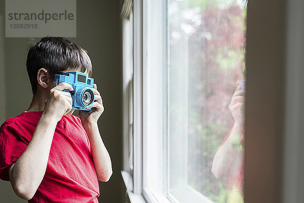 Junge fotografiert Fenster  während er zu Hause steht