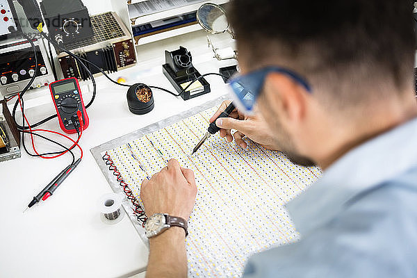 Hochwinkelansicht eines Ingenieur-Lötschaltkreises am Tisch in der Elektronikindustrie