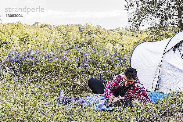 Romantisches Paar entspannt sich auf einer Decke auf einem Campingplatz im Wald