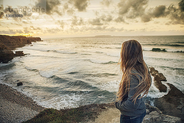 Seitenansicht einer Frau  die bei Sonnenuntergang am Strand steht