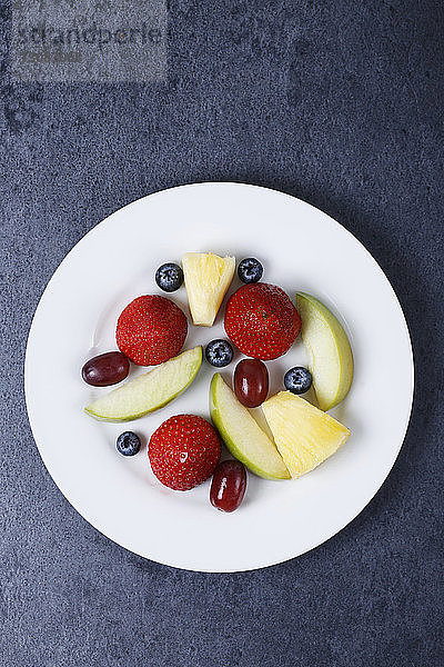 Draufsicht auf verschiedene frische Früchte in Tellerform auf dem Tisch