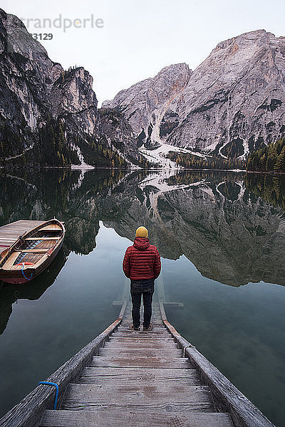 Rückansicht eines Mannes  der auf Stufen am ruhigen See vor Bergen steht