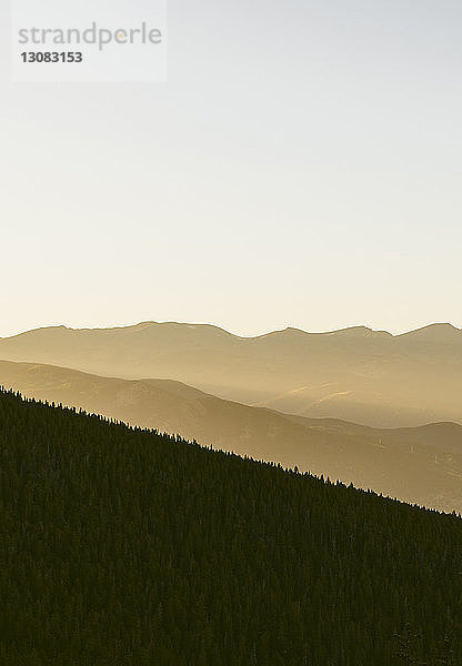 Landschaftliche Ansicht von Bäumen und Bergen vor klarem Himmel bei Sonnenuntergang