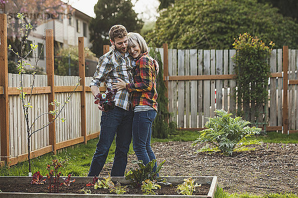 Ehepaar umarmt sich bei der Gartenarbeit im Garten