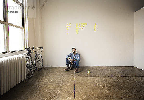 Geschäftsmann in voller Länge mit Haftnotizen an der Wand sitzend im Kreativbüro