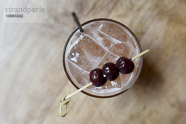 Draufsicht auf einen Cocktail mit Früchten im Trinkglas auf einem Holztisch