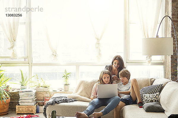 Mutter sieht Kinder an  die einen Laptop-Computer benutzen