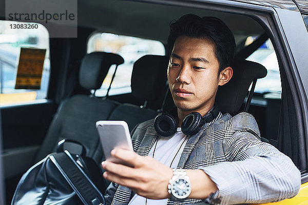 Geschäftsmann benutzt Smartphone  während er im Taxi sitzt