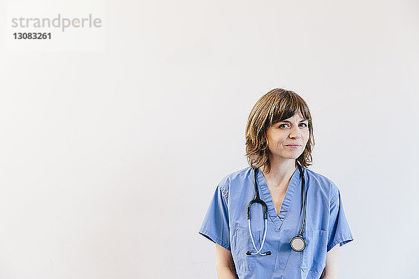 Porträt einer Ärztin mit Stethoskop vor weissem Hintergrund stehend